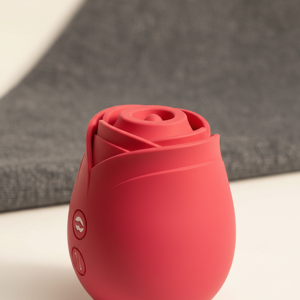 Close-up of a rose-shaped vibrator, highlighting its smooth, medical-grade silicone surface against a soft, warm cream backgr